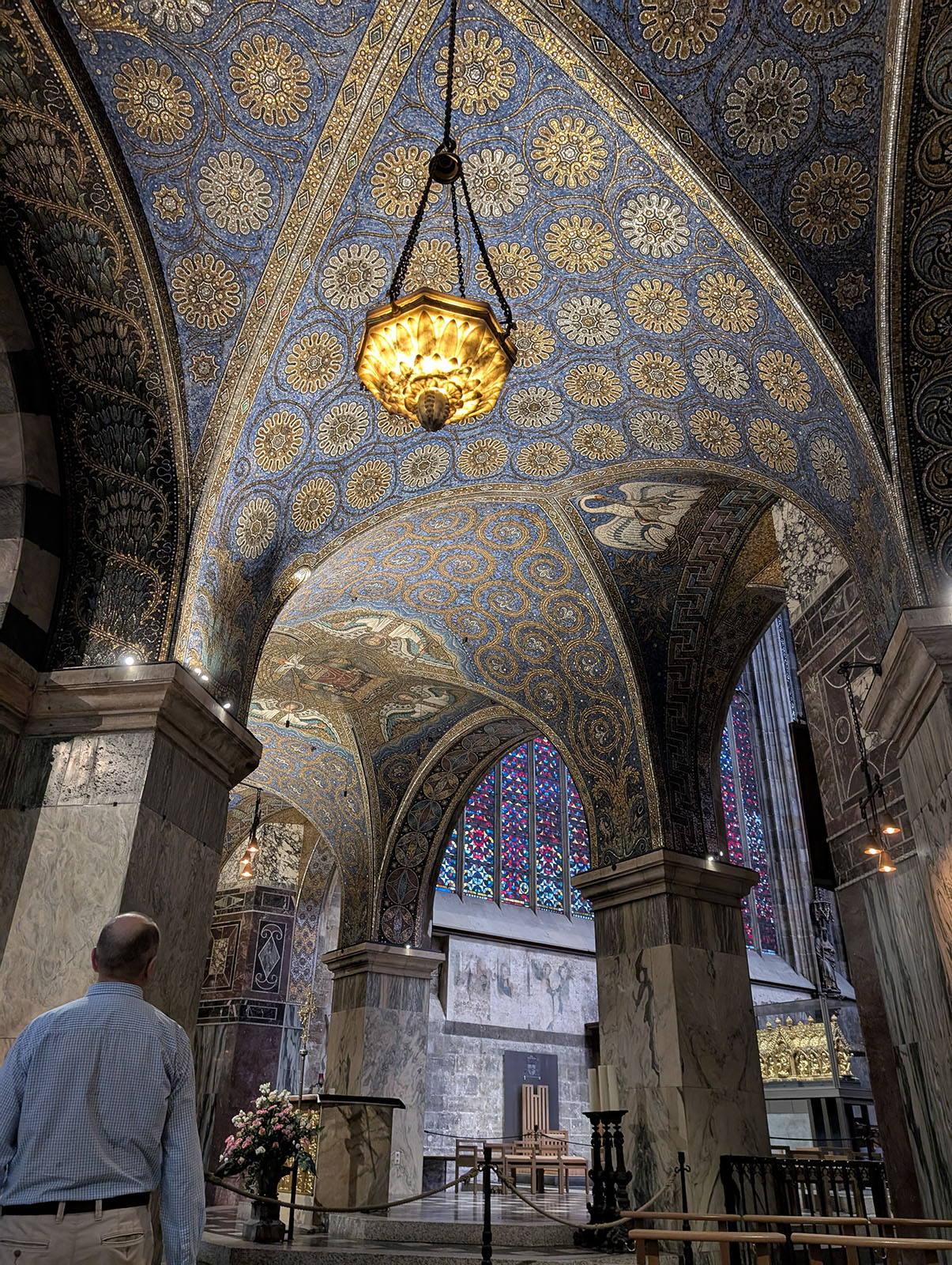 Blue and gold mosaic ceiling with a hanging lantern. Vaulting between marble-clad columns.